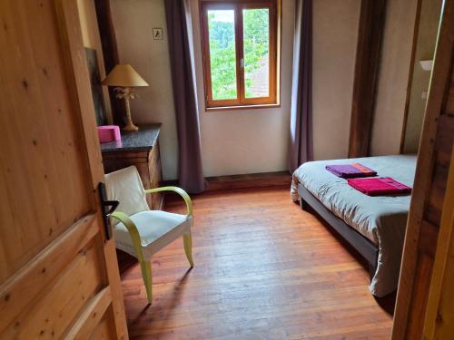 a bedroom with a bed and a chair and a window at Le Rucan Maison atypique in Montastruc-de-Salies
