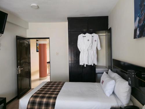 a bedroom with a bed and a robe hanging on a wall at TerraMistica Puno Centro in Puno