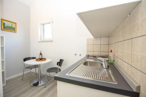 a small kitchen with a sink and a table at Apartmani Liovic in Duće