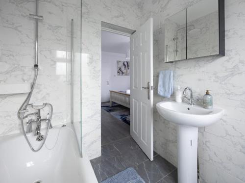 a bathroom with a shower and a sink and a tub at Reverie Escape by Halisi in Ramsgate