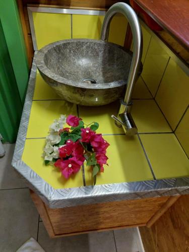 a sink with flowers on a counter in a bathroom at Méline in Baie-Mahault