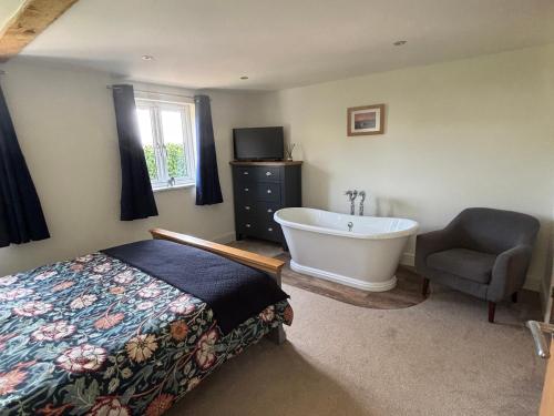 a bedroom with a tub and a bed and a chair at Ash Tree Lodge in Norwich