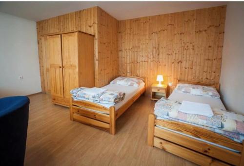 two twin beds in a room with wooden walls at Penzion u Valešů in Mohelno
