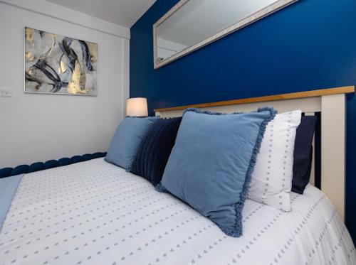 a bedroom with a bed with blue walls and a mirror at Reverie Escape by Halisi in Ramsgate