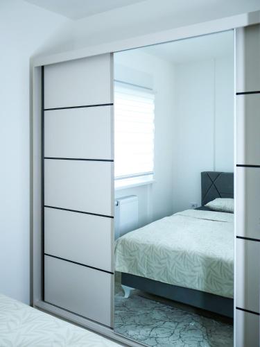 a mirrored dresser in a bedroom with a mirror at Nada Apartman in Prijedor