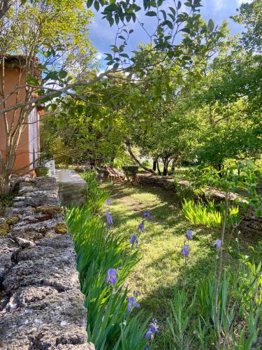 a garden with purple flowers and a stone wall at Les Iris in Bonnieux