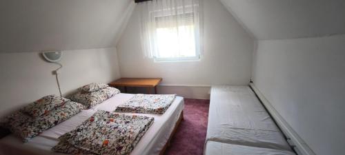 a small bedroom with two beds and a window at Hattyú Vendégház in Gárdony