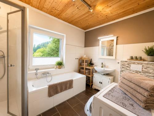 a bathroom with a tub and a sink and a window at EulenHorst - Ferienhaus in Seeboden am Millstätter See mit Sonnenterasse & Bergblick in Seeboden