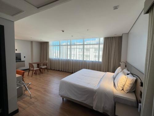 a hotel room with a bed and a table and chairs at Hotel Plaza Belmar by HCC in Campo Grande
