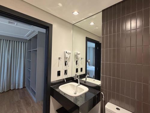 a bathroom with a sink and a mirror at Hotel Plaza Belmar by HCC in Campo Grande