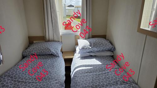 two beds in a small room with red writing on them at Sandy cove 043 in Barmouth