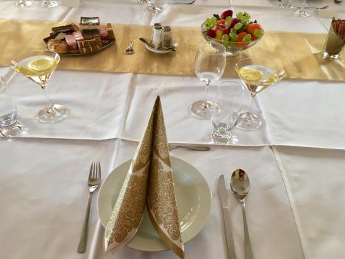a white table with a plate of food and wine glasses at Penzión Tavel in Prešov