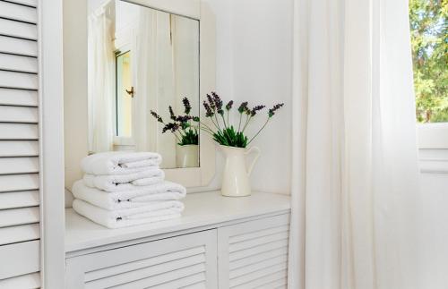 a white bathroom with a mirror and towels on a shelf at Bay View Hotel in (( Klonátika ))