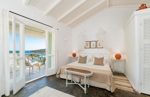 a white bedroom with a bed and a balcony at Bay View Hotel in (( Klonátika ))