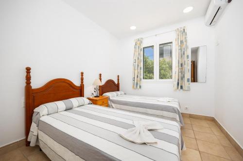two beds in a bedroom with a window at Villa Elena Dorada in Port d'Addaia