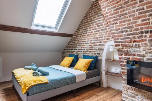 a bed in a room with a brick wall at Le 29 - T2 Calme - Confortable - Centre-ville in Valenciennes