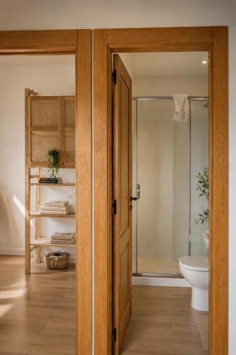 a bathroom with a toilet and a glass door at Casa Luenga in Vinuesa