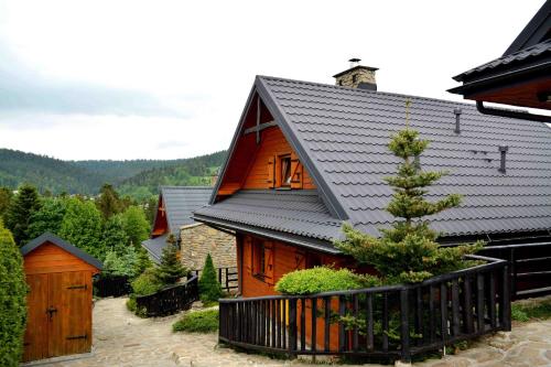 a wooden house with a black roof at Alpejskie Domy Ski House in Krynica Zdrój