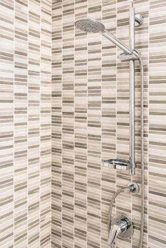 a shower in a bathroom with a tile wall at Appartamenti ABR Porto in Le Castella