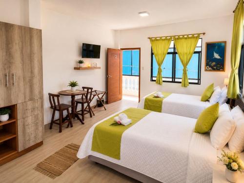 a hotel room with two beds and a table at Hostal Gardner in Puerto Ayora