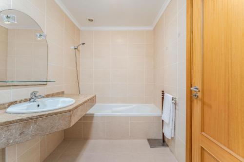 a bathroom with a sink and a bath tub at One-Bedroom Apartment near Reis Magos Beach in Caniço