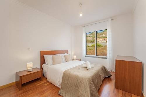 a white bedroom with a bed and a window at One-Bedroom Apartment near Reis Magos Beach in Caniço