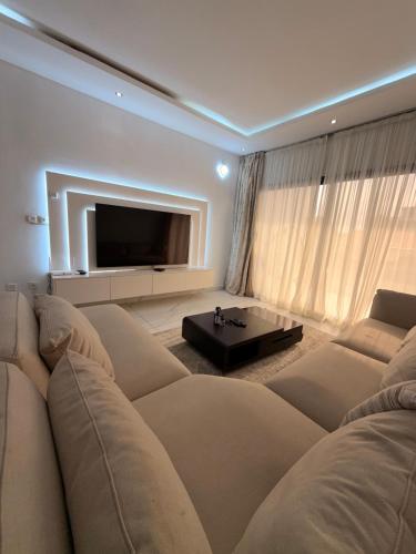 a living room with a large couch and a tv at Appartement spacieux et confortable in Abidjan