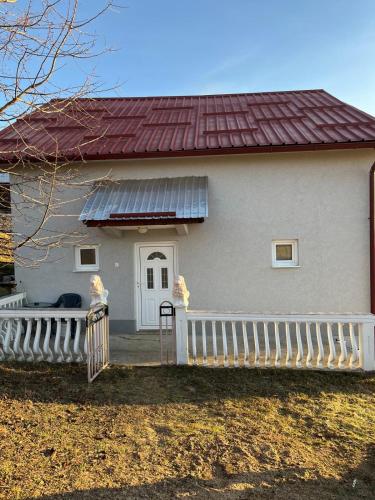a white house with a red roof and a fence at Rastoder Ponor in Petnjica
