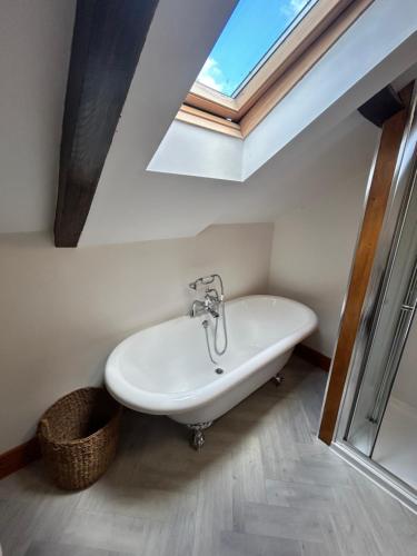 a white bath tub in a bathroom with a skylight at Herberts Cottage in Wormegay