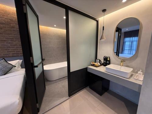 a bathroom with a sink and a mirror and a tub at Atelier Hotel Permas in Johor Bahru