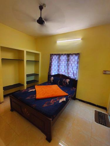 a bedroom with a bed with an orange blanket on it at AKS Cottage in Yercaud