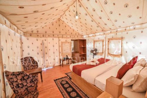 a bedroom with a bed and a chair in a room at Hostel Desert Camp Sam in Jaisalmer