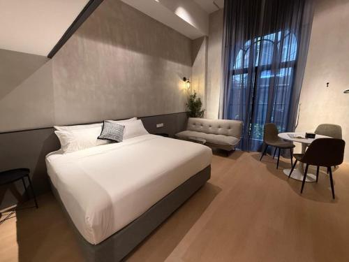 a bedroom with a large white bed and a table at Atelier Hotel Permas in Johor Bahru