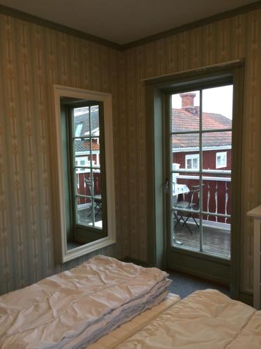 a bedroom with two windows and a bed and a balcony at Gästgivars vandrarhem och B&B in Järvsö