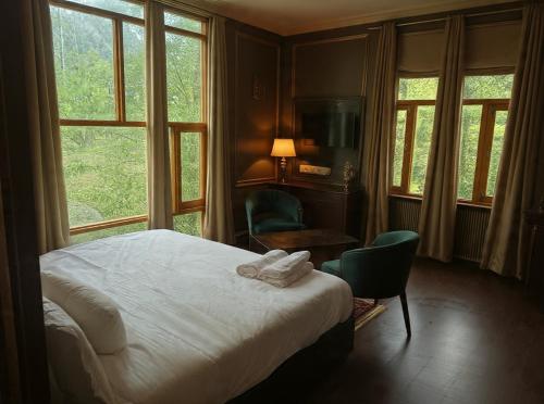 a bedroom with a bed and a chair and windows at Forest Grandeur Resort in Anantnāg
