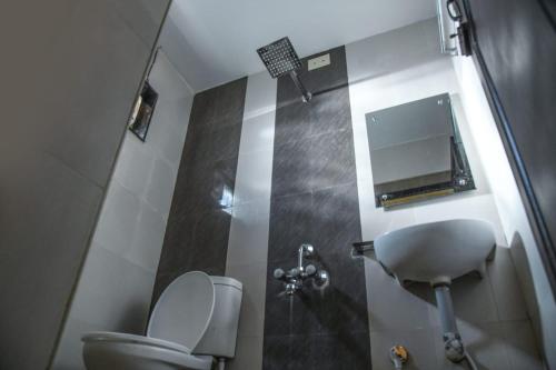 a small bathroom with a toilet and a mirror at Hotel Strawberry Grand in Rāmeswaram