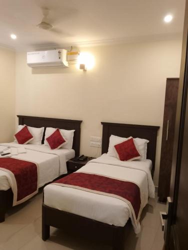 a hotel room with two beds with red pillows at Hotel Strawberry Grand in Rāmeswaram