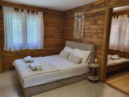 a bedroom with a white bed with wooden walls and windows at PARADISO pool&house in Prosek