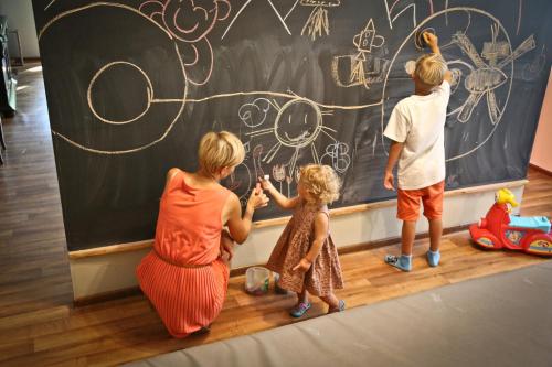 a woman and two children standing in front of a chalkboard at Drewniana Róża Domki Karkonosze in Piechowice