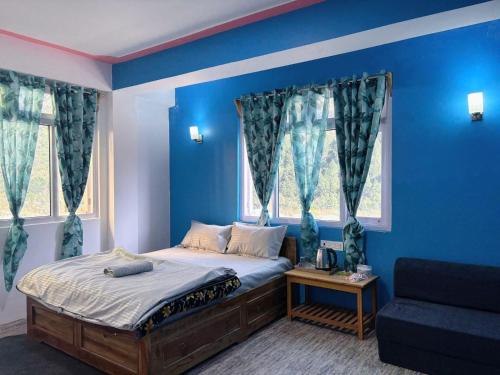 a bedroom with blue walls and a bed and a couch at Mayal Lyang Lachung in Mangan