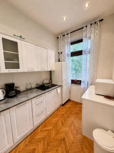 a kitchen with white cabinets and a wooden floor at Ljubez Apartment in Jajce