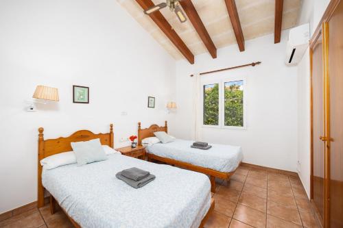 two beds in a room with white walls and a window at Villa Miguel Dos in Cala en Bosc