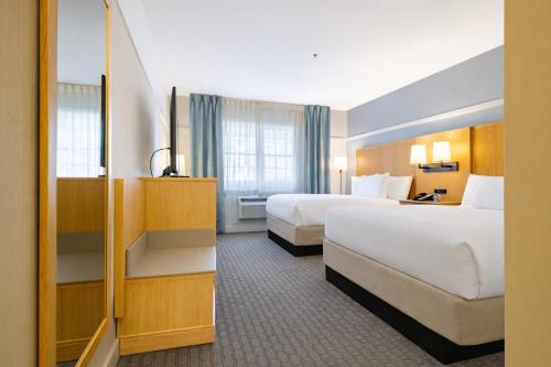 a hotel room with two beds and a mirror at Two Trees Inn in Ledyard Center