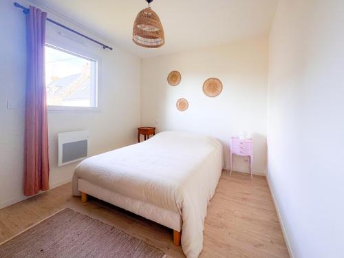 a white bedroom with a bed and a window at La Villetta Penmarch in Penmarch