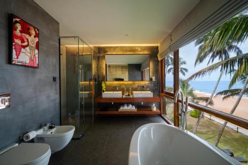 a bathroom with two sinks and a shower with the ocean at The Coast Sri Lanka, Bentota in Bentota