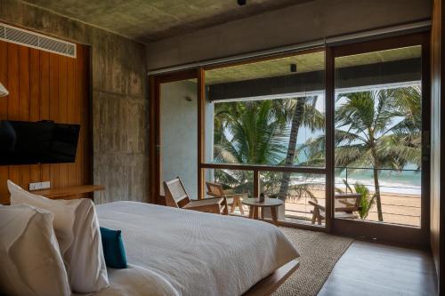 a bedroom with a bed and a view of the beach at The Coast Sri Lanka, Bentota in Bentota
