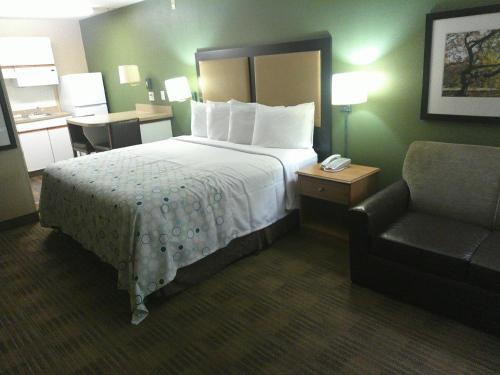 a hotel room with a bed and a chair at HomeTowne Studios by Red Roof Chantilly in Chantilly