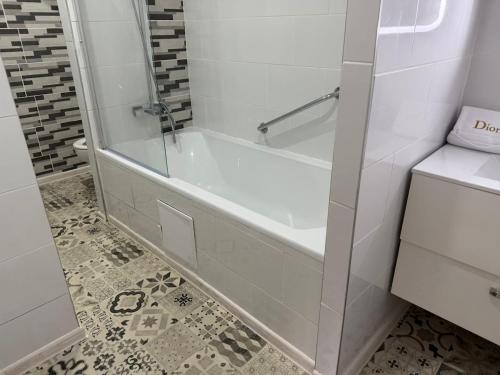a white bathroom with a tub and a tile floor at Chambre privée Moret Sur Loing in Moret-sur-Loing
