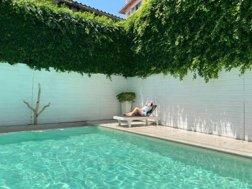 a man sitting on a bench next to a swimming pool at Royal Pavilion Hua Hin in Hua Hin