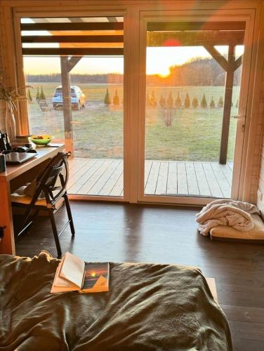 a book on a bed in a room with a sliding glass door at Medsukys - Namukai Dviem in Griniūnai